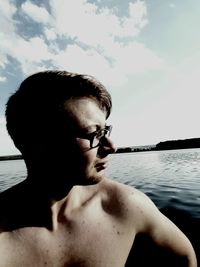 Portrait of shirtless man in lake against sky