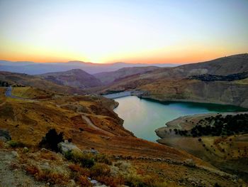 Scenic view of lake and mountains against sky during sunset