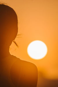 Close-up portrait of silhouette woman against orange sky