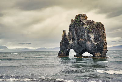 Rock formation on beach against sky