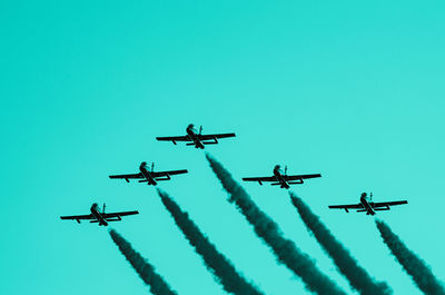 Low angle view of airplane flying against clear blue sky