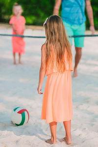 Rear view of girl playing volleyball on beach