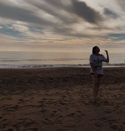 Full length of man on beach against sky during sunset