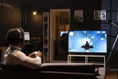 Rear view of woman using laptop at home