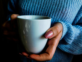 Low section of man holding coffee cup