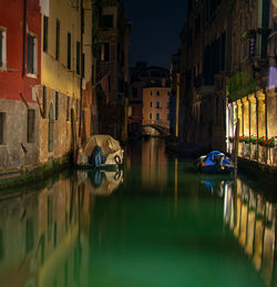 Canal amidst buildings in city of venice at night