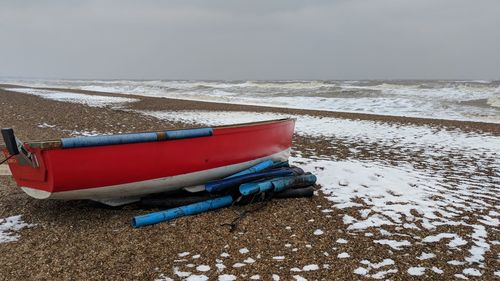 Boat moored on beach against sky during winter