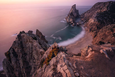 Rock formation on sea shore against sky