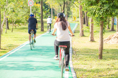 Young woman riding bicycle on footpath at park