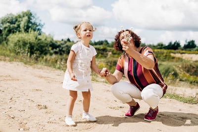 Grandmother and granddaughter are walking along a field road outside the city. an elderly woman 