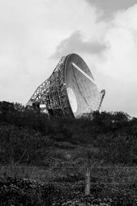 Low angle view of ferris wheel against cloudy sky
