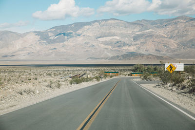 Road by mountains against sky