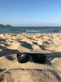 Sunglasses on beach against sky