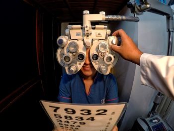 Cropped hand of doctor examining patient eyes using optical instrument