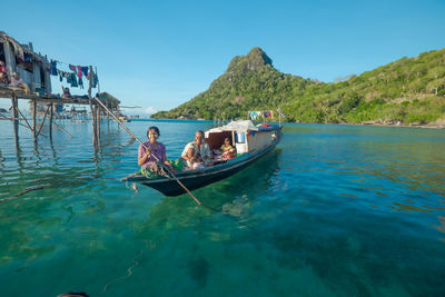 Boats in calm blue sea against clear sky