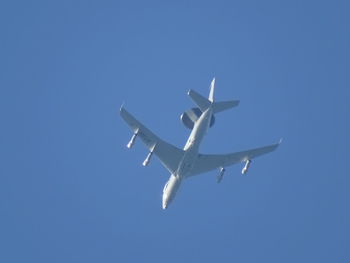 Low angle view of airplane flying against clear blue sky