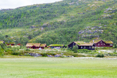 Houses on field by buildings against mountains