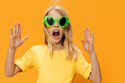 Portrait of woman wearing sunglasses against yellow background