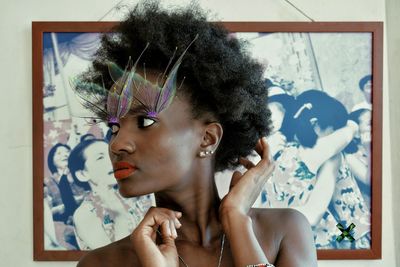 Close-up of woman with eye make-up against wall