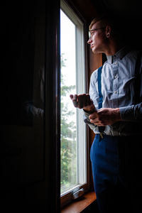 Side view of man looking through window