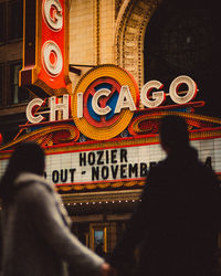 Rear view of people on illuminated building in city