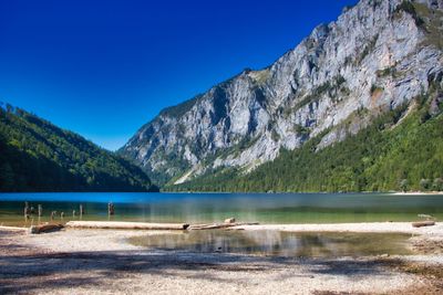 Scenic view of lake and mountains against clear blue sky