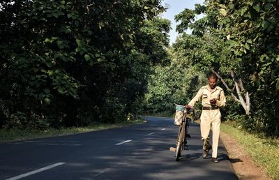 Man riding bicycle on road amidst trees