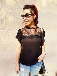 Portrait of young woman wearing sunglasses standing outdoors