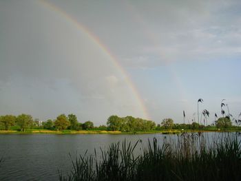 Scenic view of rainbow over lake against sky