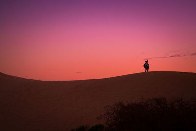 Silhouette of man on desert against sky during sunset