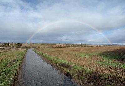 Scenic view of field against rainbow in sky