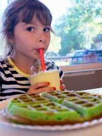 Portrait of girl drinking glass on table