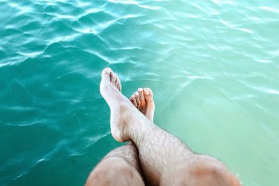 Low section of man sitting by sea