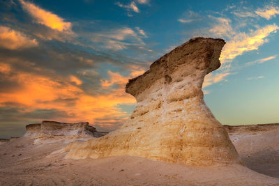 Rock formation on land against sky during sunset