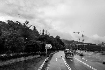 Road by trees against sky