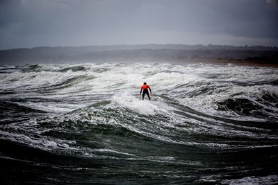 Man surfing in sea against sky