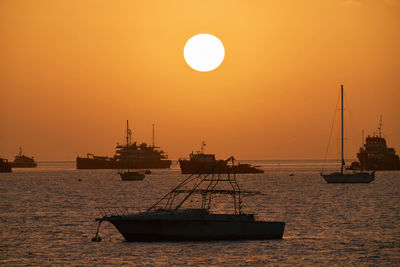 Silhouette sailboats in sea against sky during sunset