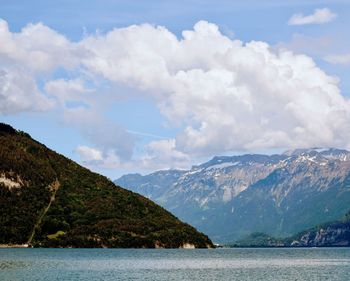 Scenic view of sea and mountains against cloudy sky