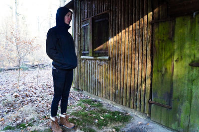 Full length of young woman standing against brick wall