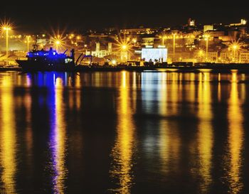 Illuminated city by river at night