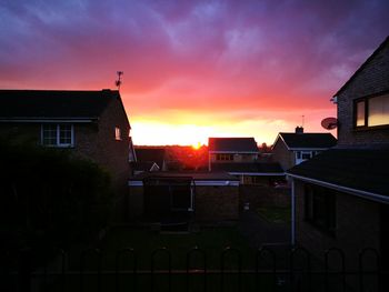 Houses in town against sky at sunset