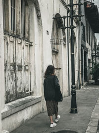 Rear view of woman walking on street amidst buildings