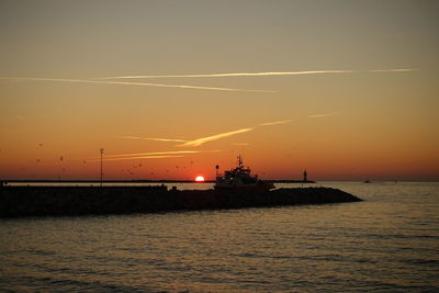 Silhouette ship in sea against sky during sunset