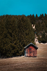 House on field by trees against sky