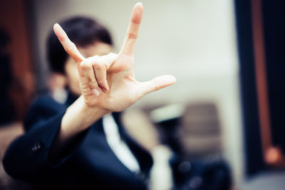 Close-up of woman showing horn gesture