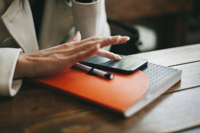 Midsection of person using mobile phone on table