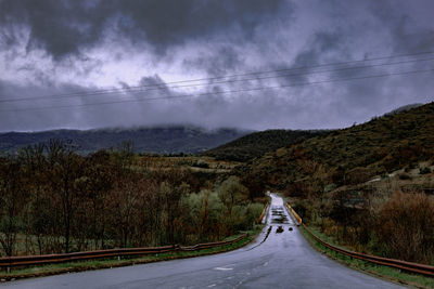 Scenic view of road by mountains against sky