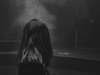 Rear view of woman standing in darkroom