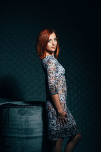 Portrait of young woman standing against wall