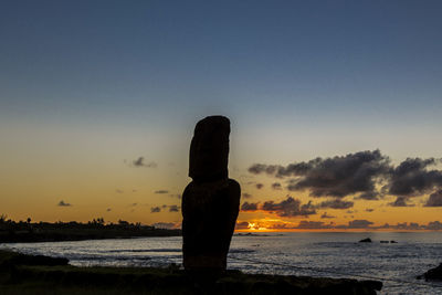 Silhouette rocks on beach against sky during sunset